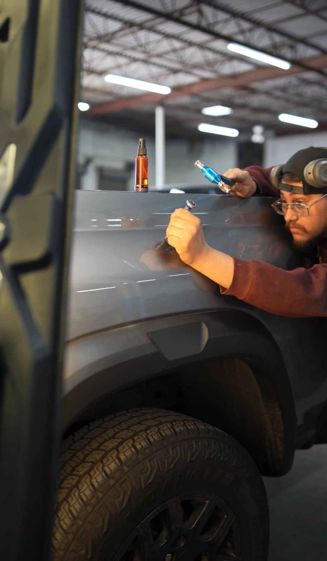 PDR technician working a dent from behind a body panel
