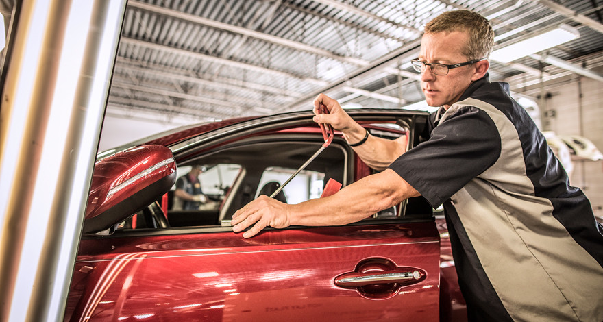 Technician using paintless dent repair rods on a hail-damaged roof