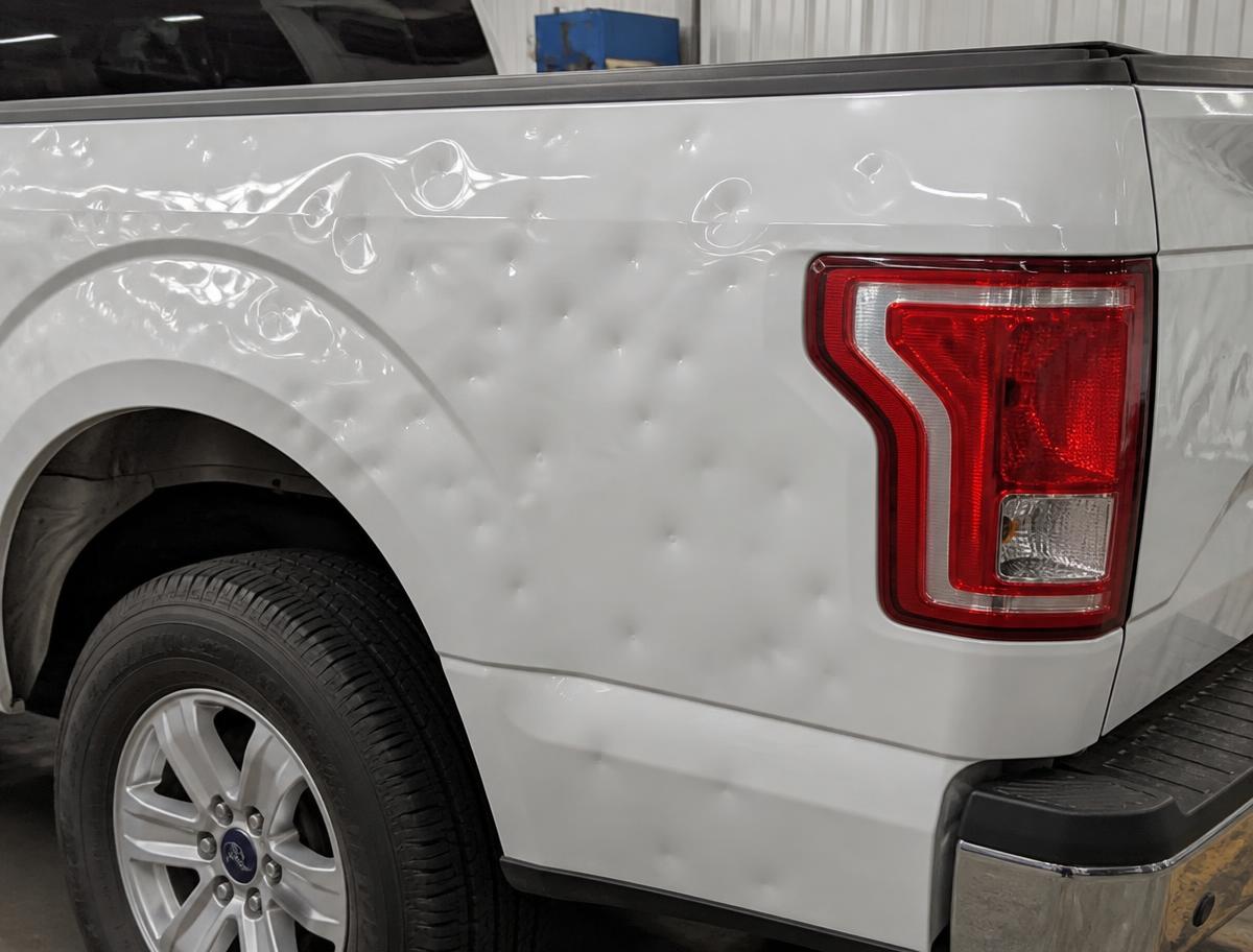 Hail damage before paintless dent repair — Truck bedside — deep dents